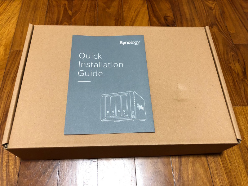 Synology DS418 quick installation guide on box containing cables and screws