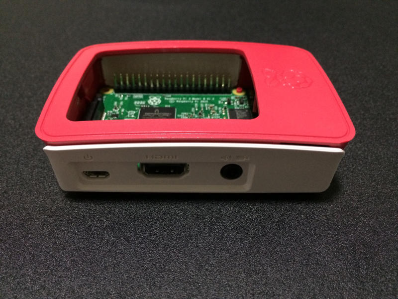 White piece with port openings of Official Case attached to red parts and Raspberry Pi 3 Board